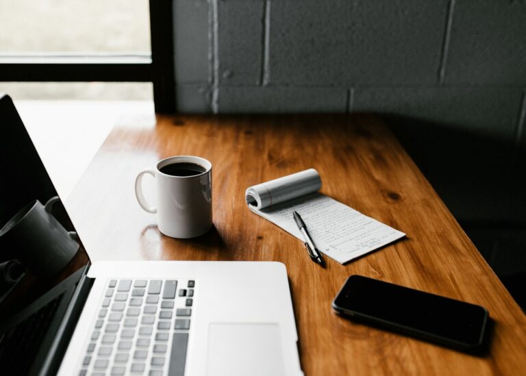 A laptop, notebook and coffee on a desk while comparing platforms